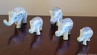 Five blue and white porcelain elephants arranged on a surface, showing size differences and overall design.