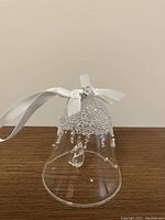 Clear glass Swarovski bell ornament with intricate crystal beadwork and white ribbon