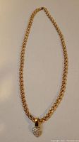 Full view of the gold chain with heart-shaped pendant.