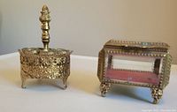 Copper and glass trinket box with footed base and lined interior shown alongside the filigree holder for scale and detail comparison.