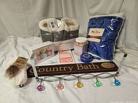 Full view of all items in the lot including foot massager, slippers, bath salts, bath bombs, creams, blanket, sign, and hook rack