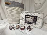 Full lot including cotton rope basket with leather handles, queen duvet cover set in original packaging with gray circle embroidery, and four soy candles in floral decorative tins with box.