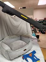 Photo showing Pet Gear dog ramp extended above gray Wags & Smiles dog bed and blue Superman dog harness in foreground