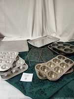 Photo showing entire 12-piece baking set consisting of cookie sheets, cooling racks, and various muffin pans, all metal with silver finish.