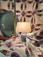 Full view of the quilt backdrop, oval vintage mirror with carved blue frame, and 15-inch blue ceramic lamp with rectangular shade, showing scale with measuring tape.