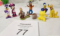 Overview of all colorful vintage Disney character figurines plus bears and bunny arranged together on white background.