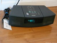 Front view of Bose Wave Radio/CD unit powered on, showing digital display with FM radio frequency.