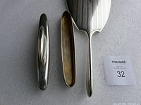 Photo showing the hand mirror, nail buffer, and its matching silver case laid on a surface