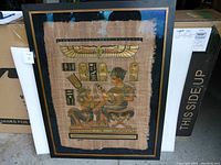 Full view of large framed papyrus print depicting an ancient Egyptian scene with hieroglyphs and symbols.