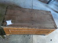 Top view of the wooden blanket box showing worn and bare surface of the lid with included material cover removed.