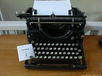 Front view of black vintage Underwood typewriter with white round keys and brand name in center.