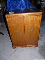 Front view of vintage wooden music chest with two doors and glass top