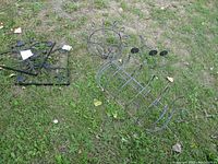 Photo showing black metal corner decorative brackets and a curved planter holder on grass