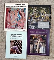 Four art books arranged on carpeted floor showing front covers, titles and cover artwork.