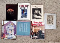 Photo showing seven art books arranged on carpet; titles visible include Chagall’s World, Georges Seurat, Klee, The Artist in His Studio, and Important Modern Artists.