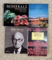 Four hardcover art and design books arranged on carpet. Titles visible: Minerals, Frank Lloyd Wright, Philip Johnson: The Architect in His Own Words, Mexican Patterns.