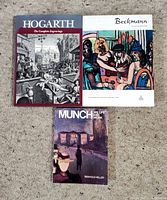 Photo of three art books: Hogarth, Beckmann, and Munch, laid flat on a carpet surface