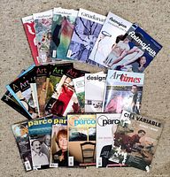25 assorted art magazines laid out on a beige carpet with varied colorful covers featuring artworks and artists.