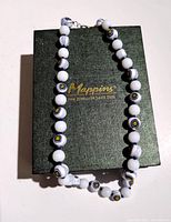 Beaded necklace arranged on closed Mappins Jewellers box showing length and bead pattern.