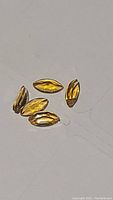 Five marquis cut yellow sapphire gemstones arranged on a flat surface showing transparency and yellow color.