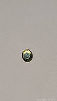 Photo of oval cut sapphire showing deep golden yellow and blue colors on flat surface, highlighting its color and luster.