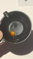 Loose orange Ethiopian fire opal shown in a small black container, highlighting the vibrant color.