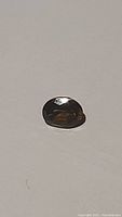 Top view of oval cut natural Madeira citrine gemstone showing dark, deep cognac color and faceting.