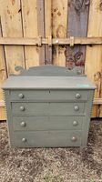 Front view showing four drawers, scalloped backboard, and worn green paint.