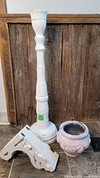 All three items: tall white candle stick holder, white wooden antique shelf bracket, and white concrete planter set against wood and tiled background