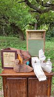 Full lot displayed outdoors on wooden furniture showing washboard, wall art, wooden ducks, corbels, and wooden box