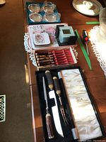 Top-down view of carving set, coasters, placemats and boxes displayed on table.