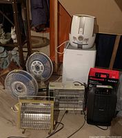 Lot of two beige-blue electric fans, three electric heaters including Honeywell ceramic heater, white AOMA dehumidifier and Cool Mist humidifier. Untested condition visible.