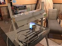 Full view of metal Gro-Light on table showing metal frame, wiring, and attached timer device.