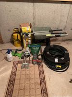 Full view of all items including fertilizer and seeder wheelbarrow, garden sprayers, grass seed bag, and hoses.