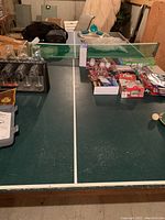 Top view of green folding ping pong table with white center line and items on surface.