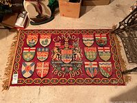 Full view of the Canadian Centennial rug laid flat on floor showing all shields and central coat of arms.