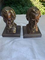 Front angle view of both metal Abraham Lincoln bust bookends side by side on white cloth.