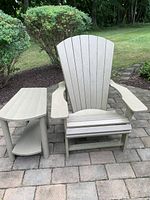 Front view of beige Adirondack chair and matching side table on stone patio.