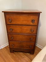 Front view of antique four-drawer wooden chest with wood knobs.