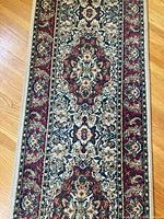 Close-up photo focusing on the center floral medallion and border to show rug texture and color details.