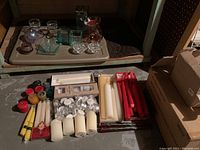Photo showing all candles and candle holders laid out on the floor, including tapers, pillars, tealights, votives, and various glass holders.
