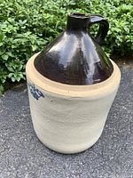 3 gallon farmhouse primitive crown jug showing dark brown glazed top, handle, and light unglazed bottom with blue crown emblem