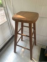 Side view of the wooden stool showing height and leg structure