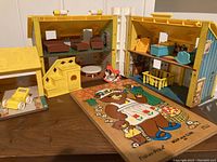 Full display of Fisher Price Family Dollhouse with various miniature furniture items and accessories alongside child's wooden bear family puzzle