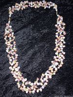 Full view of the multi-strand pearl necklace laid flat, showing the dense clustering of pearls and stones.