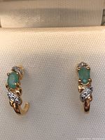 Pair of small post earrings with oval genuine emeralds set in gold over sterling with a twisted design and white stones