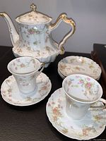 Set showing teapot with lid, two cups on saucers, and stack of saucers.