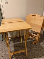 View showing two of the tray tables set up and two folded along with the wooden stand on the right.