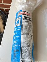 Close-up of Film-Gard heavy duty plastic sheeting roll packaging showing size, thickness, and uses.