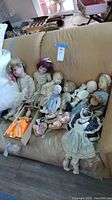 Wide view of all antique dolls on couch showing various sizes and conditions including fragile porcelain heads.